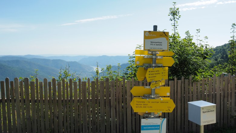 Wegweiser im Naturpark mit Bergblick und Holzzaun im Vordergrund., © Donau NÖ/JMZ