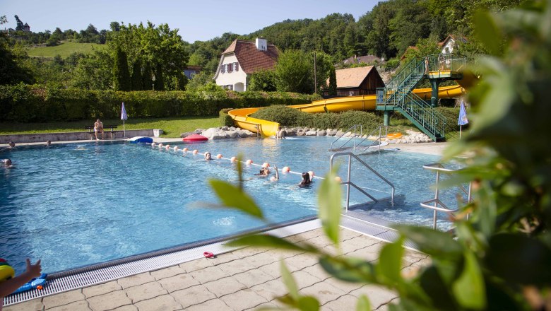 Freibad mit gelber Rutsche, umgeben von grüner Landschaft und Häusern., © Donau_Niederoesterreich_Barbara_Elser