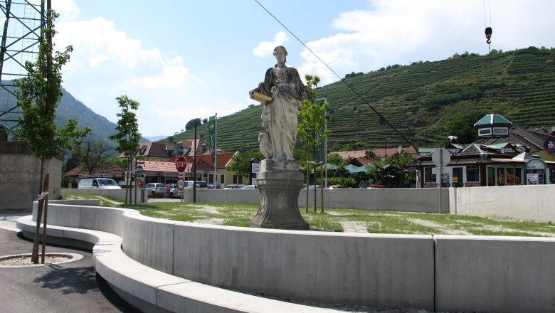 Statue auf Platz mit Weinbergen im Hintergrund, sonniger Tag., © Donau NÖ_BF