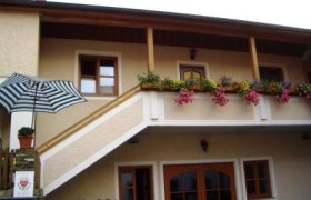 Haus mit Balkon, Blumen und gestreiftem Sonnenschirm., © Schütz Hermine