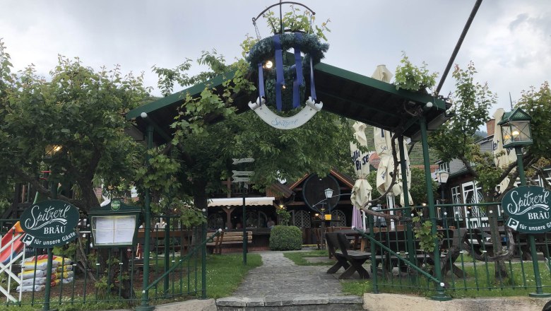 Eingang zu einem Biergarten mit grüner Überdachung und Sitzbereich., © Donau Nö Tourismus GmbH