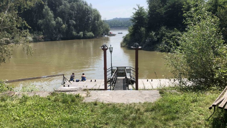 Flussufer mit Steg, zwei Personen sitzen am Wasser, umgeben von Bäumen., © Donau NÖ Tourismus GmbH