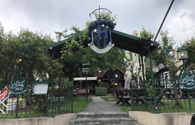 Eingang zu einem Biergarten mit grüner Überdachung und Sitzbereich., © Donau Nö Tourismus GmbH