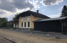 Kleiner Bahnhof Emmersdorf mit gelbem Gebäude und bewölktem Himmel., © Donau NÖ Tourismus