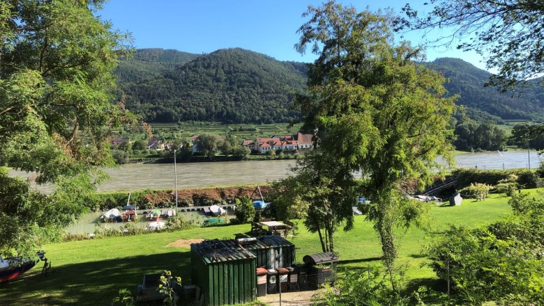 Grüne Landschaft mit Fluss, Booten und Hügeln im Hintergrund., © Donau NÖ Tourismus