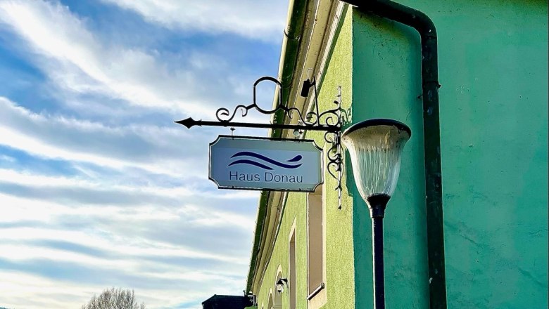 Grünes Gebäude mit Schild 'Haus Donau' und Laterne, blauer Himmel., © Haus Donau, Hr. Benesics